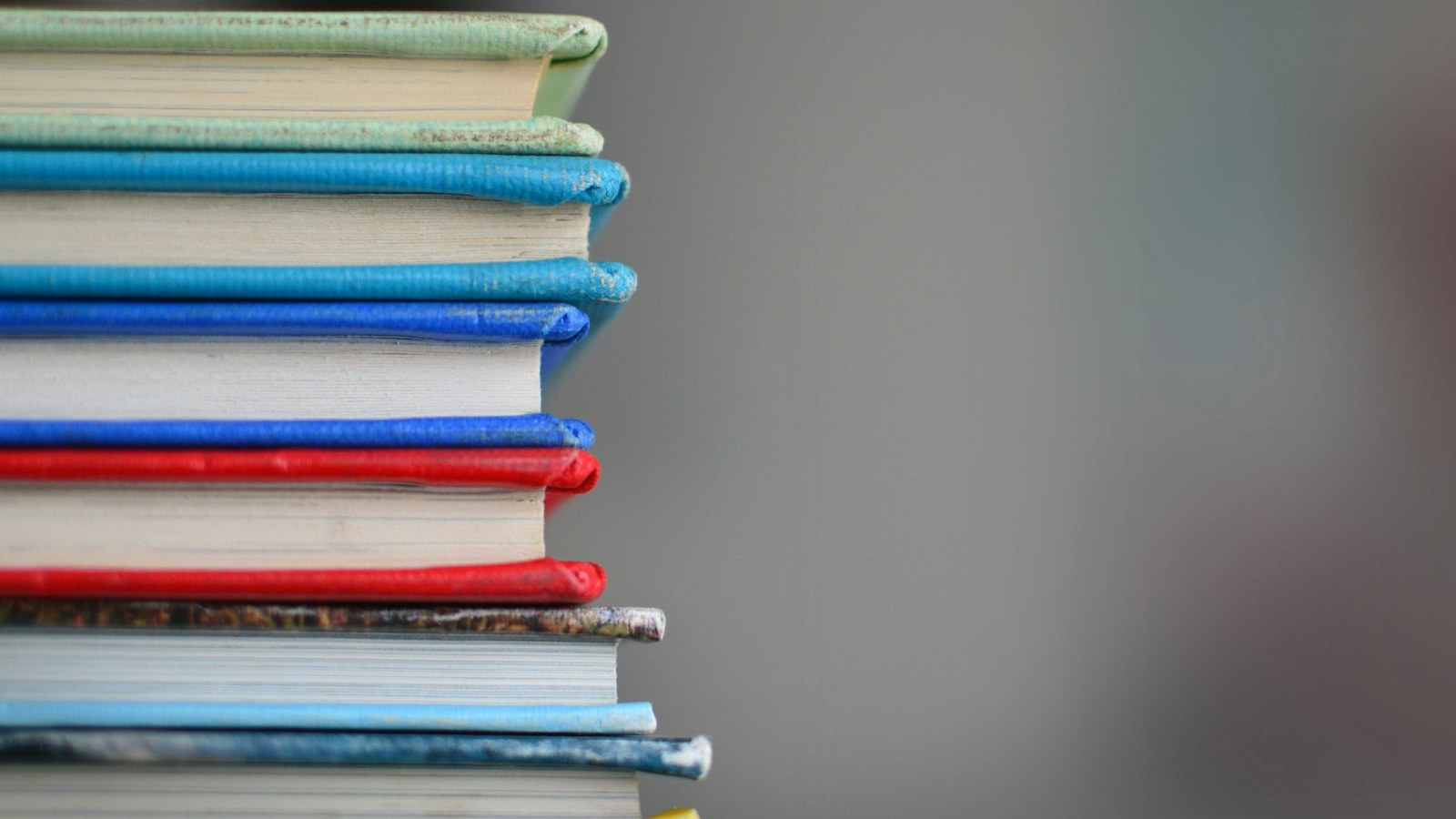 Stack of open books on a table — handbook and practice before the real exam.